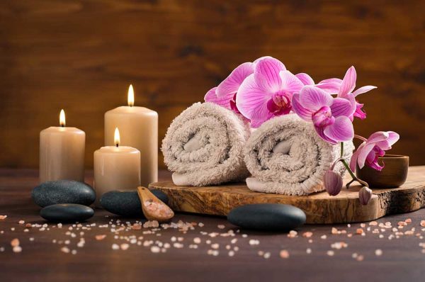 Kumpang Thai Massage spa setting with brown rolled towel orchids candles wood