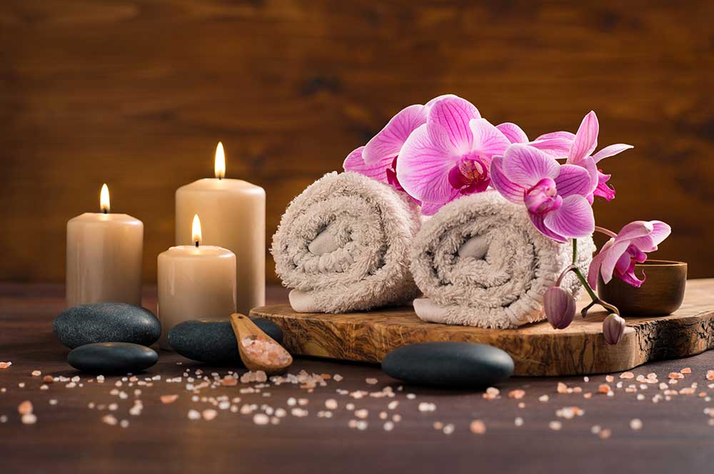 Kumpang Thai Massage spa setting with brown rolled towel orchids candles wood